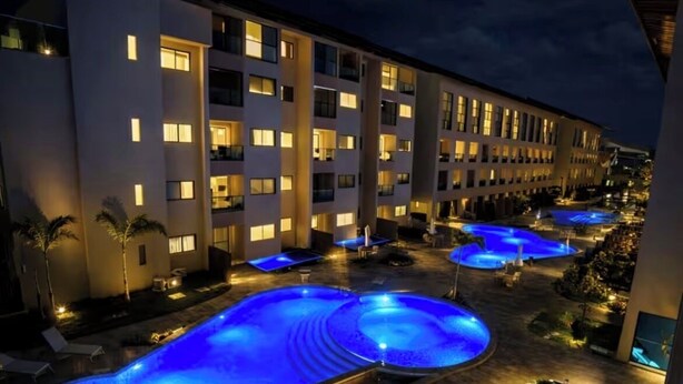 Ett hotell med flera pooler och en väl upplyst fasad på natten.