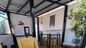A spacious room with a yellow armchair, a wooden table with a colorful decorative item, and a sofa. - Haku Hostel Cusco (Cusco)