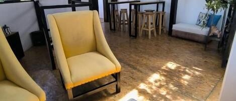 Una habitación amplia con un sillón amarillo, una mesa de madera y un adorno decorativo de colores, además de un sofá.