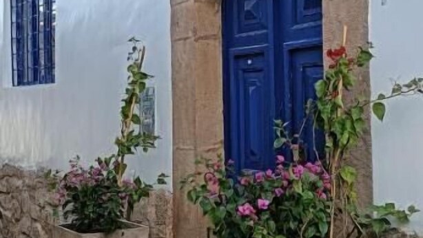 A white building with blue doors and windows, stone steps, and potted plants. - Haku Hostel Cusco (Cusco)