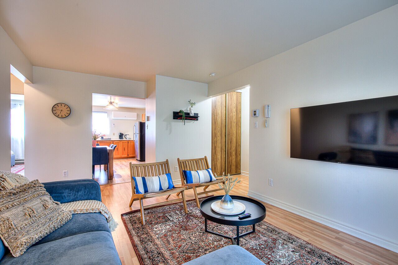A modern living room with a sofa, two chairs, a coffee table, and a TV.