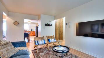 A modern living room with a sofa, two chairs, a coffee table, and a TV.