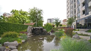 Een aangelegde tuin met een vijver, rotsen en begroeiing.
