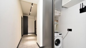 Een moderne wasserette met een wasmachine, een droger en een plank met opgevouwen handdoeken.
