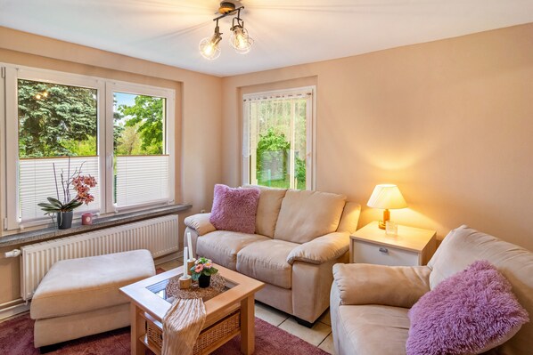 Een gezellige woonkamer met een beige bank, een houten salontafel en een lamp op een nachtkastje.
