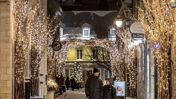 A snow-covered street with buildings adorned with lights, a dog, and people walking. - Montreal`s West Island Retreat! Value & Adventure! (Montréal)