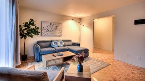 A modern living room with a sectional sofa, a coffee table, a potted plant, and a floor lamp. - Montreal`s West Island Retreat! Value & Adventure! (Montréal)