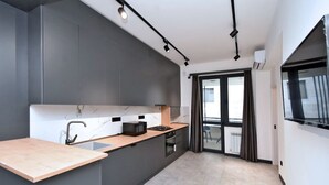 A modern kitchen with dark cabinetry, a marble backsplash, and a wooden countertop. - Cozy 1-bedroom apartment in adorable Yerevan with AC and Balcony (Yerevan)