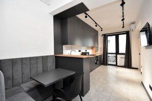 Eine moderne Küche mit integrierter Kücheninsel, einem Essbereich mit einer Bank und einem an der Wand montierten Fernseher.