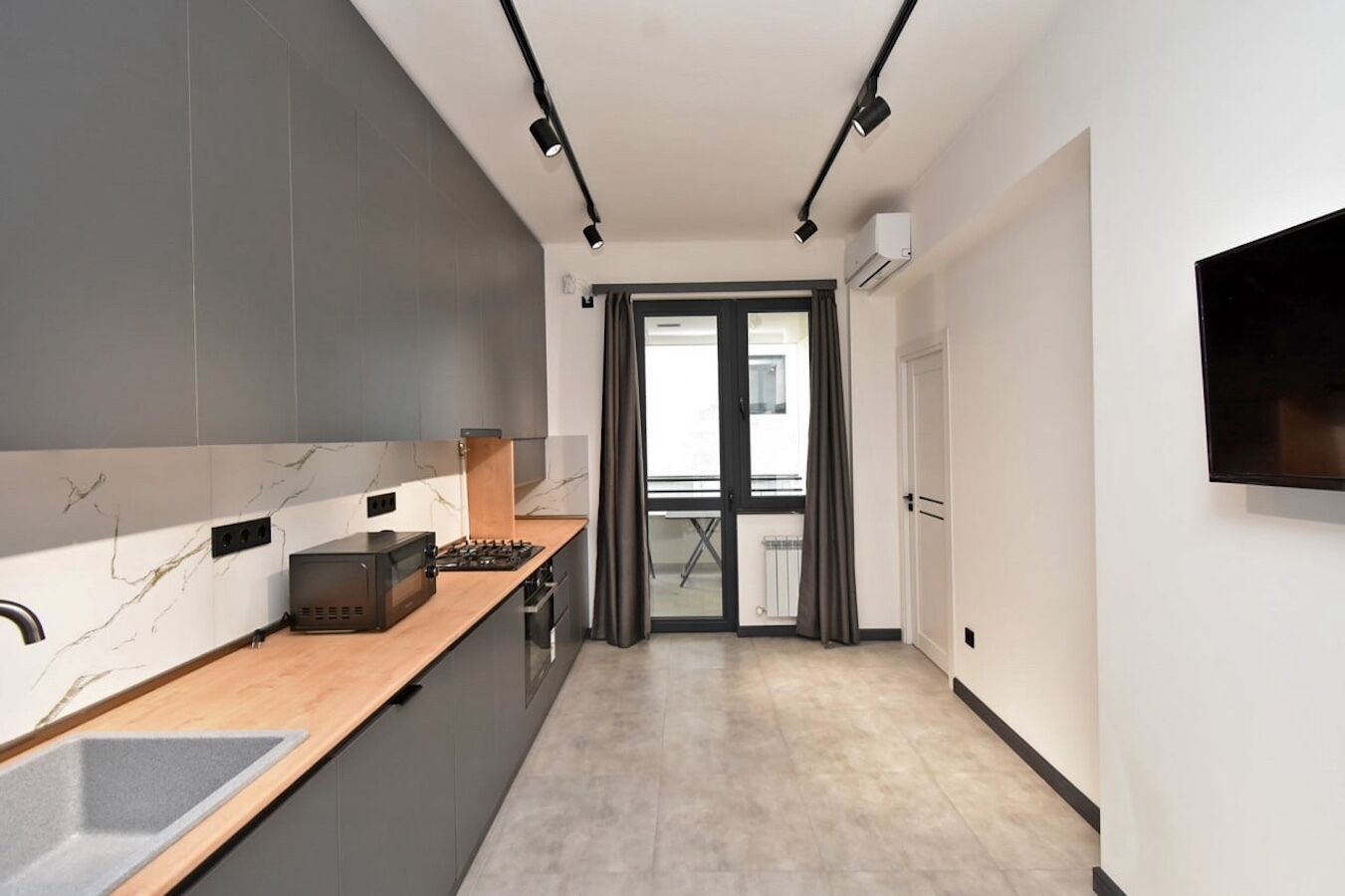 A modern kitchen with a marble backsplash, a wooden countertop, and a built-in stove.