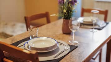 Une table à manger dressée avec des assiettes, des couverts et un verre.