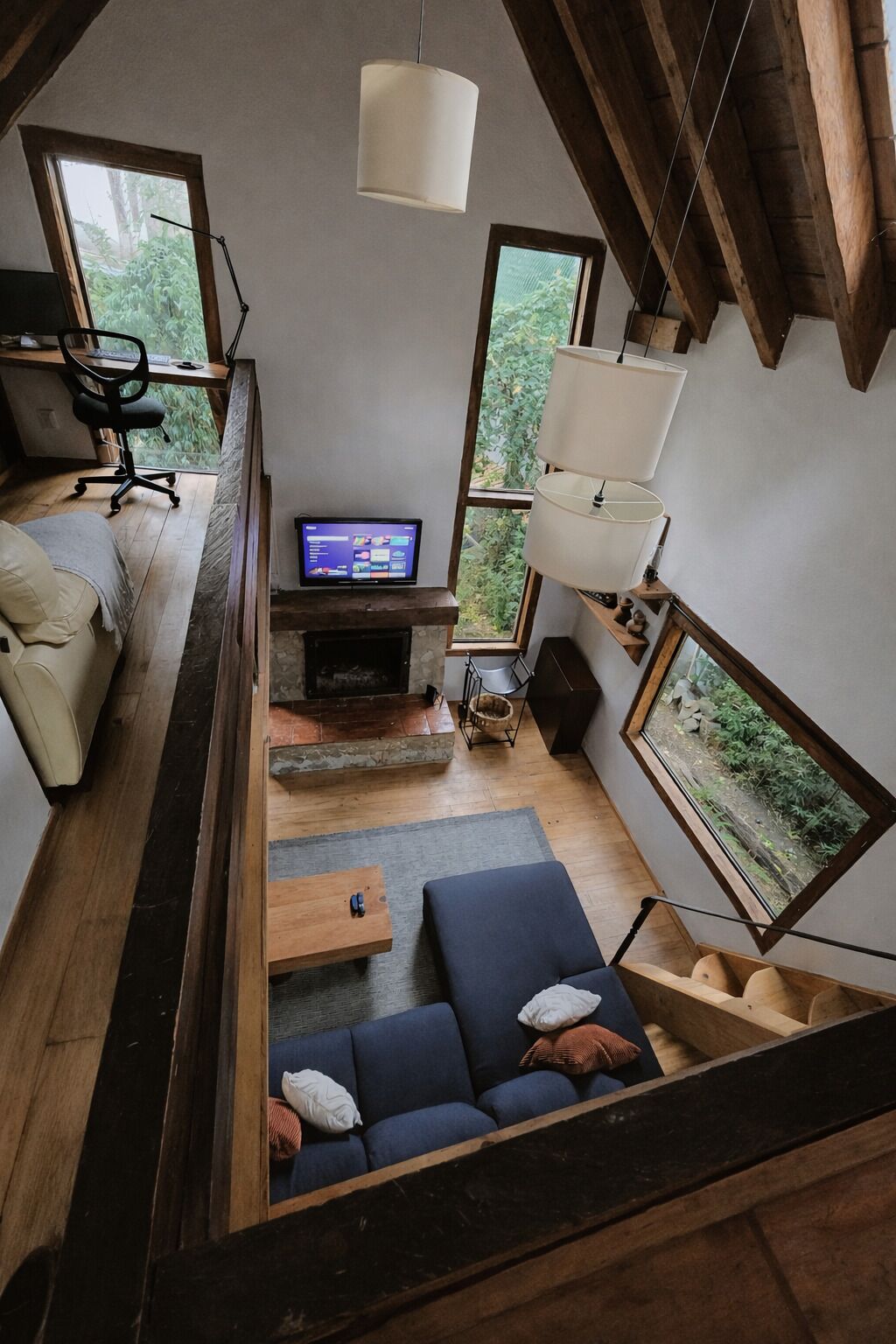 A modern loft-style living room with a sofa, a coffee table, a fireplace, and a television.