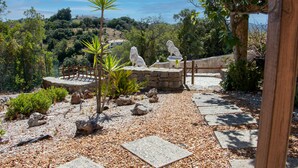 A garden with stone statues, a wooden bridge, and a stone pathway.