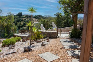 Ein Garten mit Steinfiguren, einer Holzbrücke und einem Steinweg.