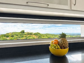 A kitchen with a window view of a green landscape. - Villa Topázio - Private Pool, Sea views, Airco (São Brás de Alportel)
