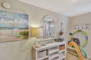 A room with a beach-themed painting, a console table with decorative items, a mirror, and a trampoline. - 4 bedroom - 4.5 bath condo.  With Ocean views. (Saint Simons Island)