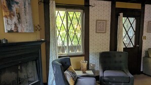 Una sala de estar con chimenea, dos sillones, una mesa de centro y un cuadro en la pared.