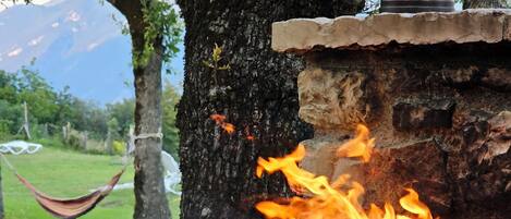 Una copa de vino blanco sobre un alféizar de piedra, con un fuego ardiendo al fondo.