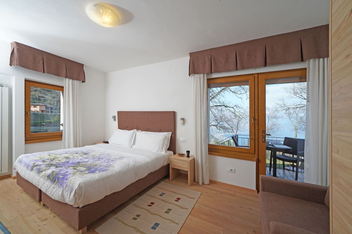 A bedroom with a bed, bedside table, and a view of the outdoors.