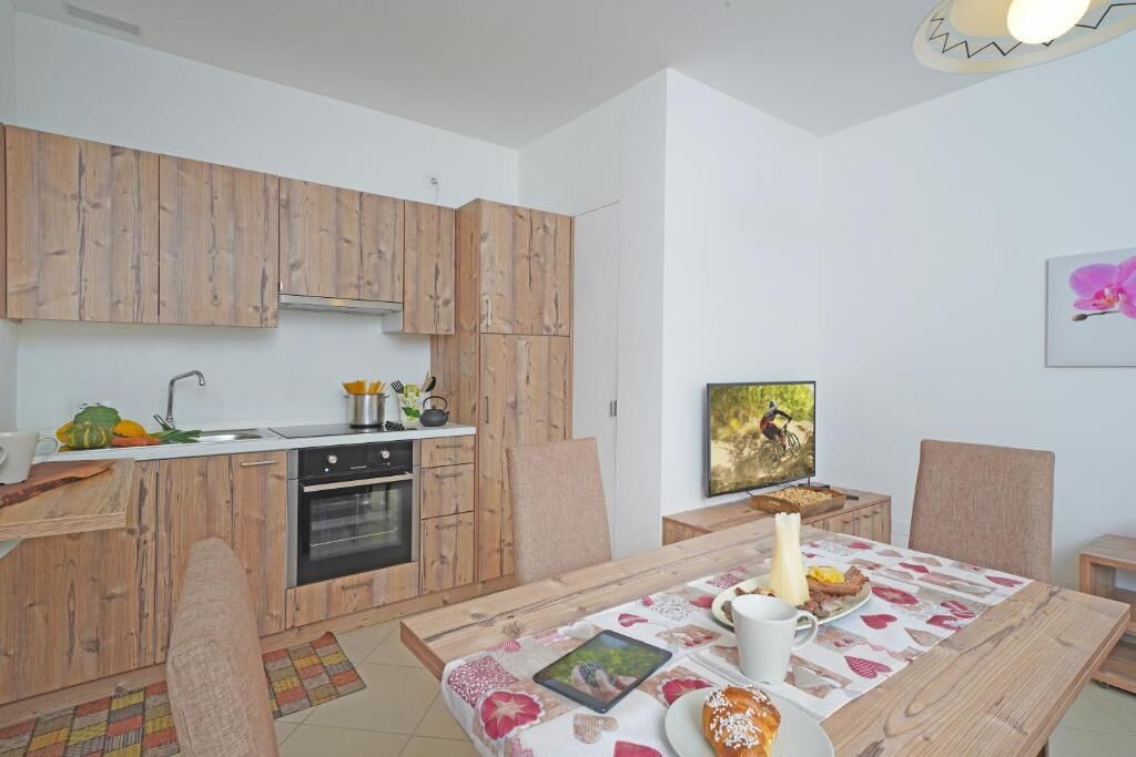 A compact kitchen with wooden cabinets, a built-in oven, and a dining area with a table set for breakfast.
