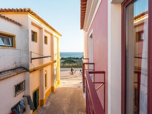 Un callejón estrecho con un edificio a la derecha y vista al mar.