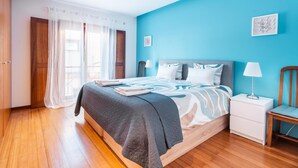 A bedroom with a bed, bedside tables, a chair, and a window with curtains. - Casa Da Bélgica: Sea View, WiFi & Air Conditioning in Sagres (Sagres)