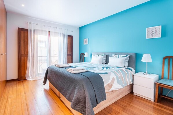A bedroom with a bed, bedside tables, a chair, and a window with curtains.
