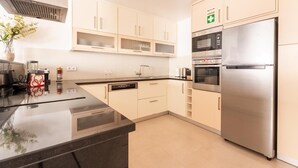 A modern kitchen with a stainless steel refrigerator, built-in oven, and microwave. There is a sink with a faucet, and the cabinets are light-colored. - Casa Da Bélgica: Sea View, WiFi & Air Conditioning in Sagres (Sagres)