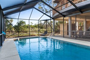A swimming pool with a covered area, lounge chairs, and a view of the surrounding landscape. - Canary On The Bay: Bayfront, Pool, Pet-friendly, Shared Dock, Sleeps 14 (St. George Island)