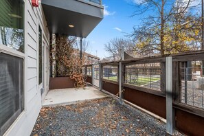 A covered outdoor area with a gravel path, a metal fence, and a view of a sports field. - Exceptional 2BR in Prime Location Top Amenities (Austin)