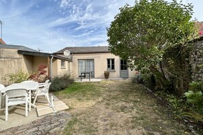 Ein Haus mit einer kleinen Terrasse, einem Tisch und Stühlen.