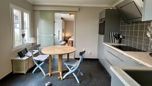 Eine moderne Küche mit Essbereich, einem eingebauten Backofen und Blick in den angrenzenden Raum.
