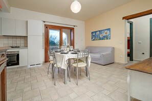 Una cucina con un tavolo da pranzo per quattro persone, un divano e un quadro appeso al muro.