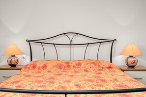 A bed with a floral bedspread, two bedside lamps, and a plain wall. - Apartment 'Trilo La Rosa' with Shared Pool, Shared Terrace and Air Conditioning (Monte Petrosu)