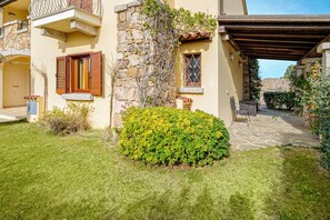 A building with stone walls, wooden shutters, and a covered patio area. - Apartment 'Trilo La Rosa' with Shared Pool, Shared Terrace and Air Conditioning (Monte Petrosu)