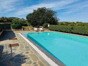 Una piscina rettangolare con bordo in pietra e cancello in metallo.