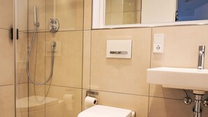 Ein modernes Badezimmer mit Duschkabine, Toilette und Waschbecken mit Spiegel.