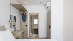 Et moderne hotelværelse med en stor seng, et trænatbord, et spejl og et badeværelse, der kan ses gennem en åben dør.