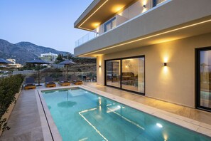 A modern poolside area with a clear view of the pool, lounge chairs, and a mountain backdrop. - Deluxe Villa Celeste - Sea View and Private Pool (Mylopotamos)