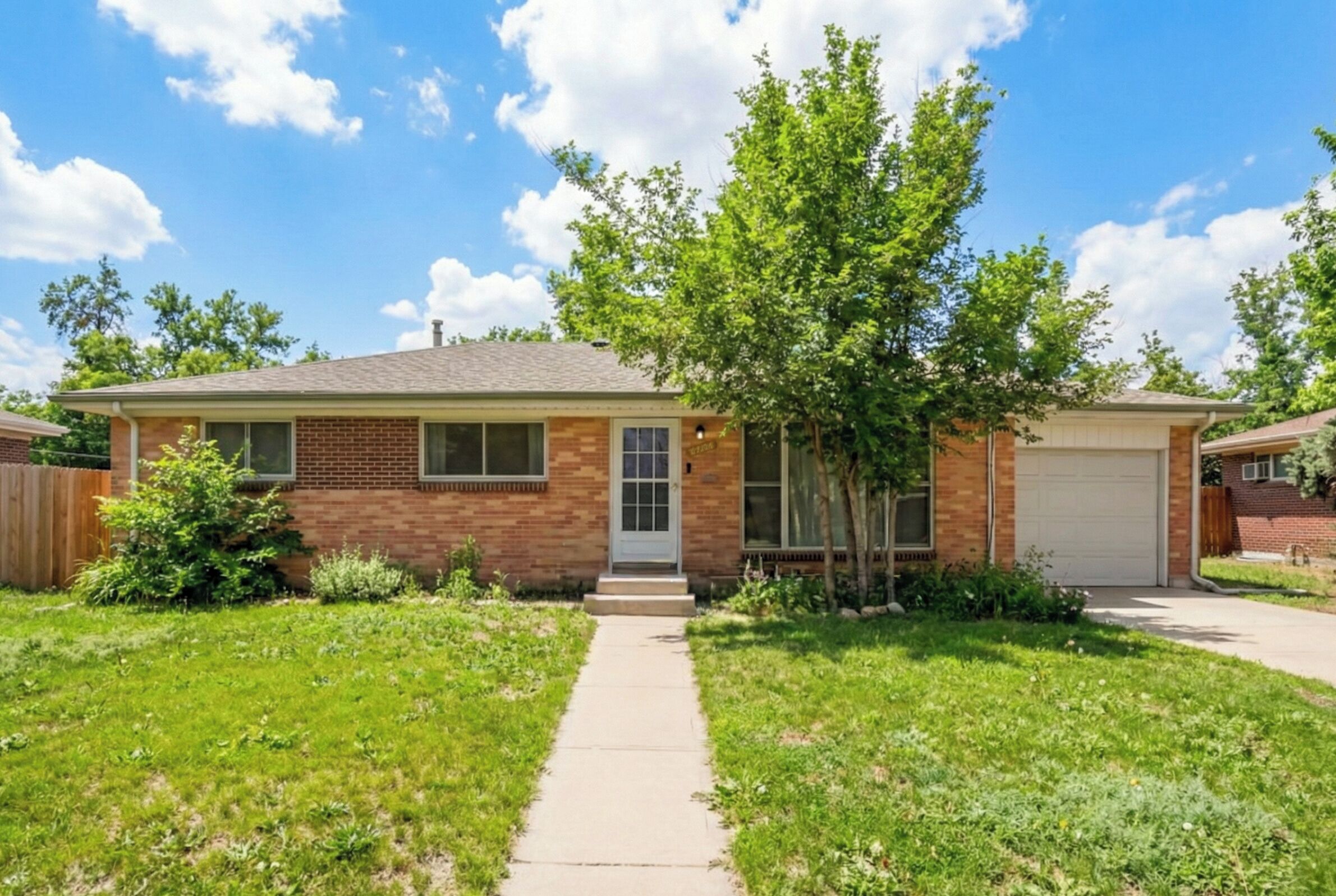 A two-story house with a brick facade, a front garage, and a well-maintained lawn.