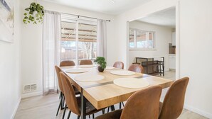 Een eetgedeelte met een lange houten tafel, meerdere stoelen en een potplant.