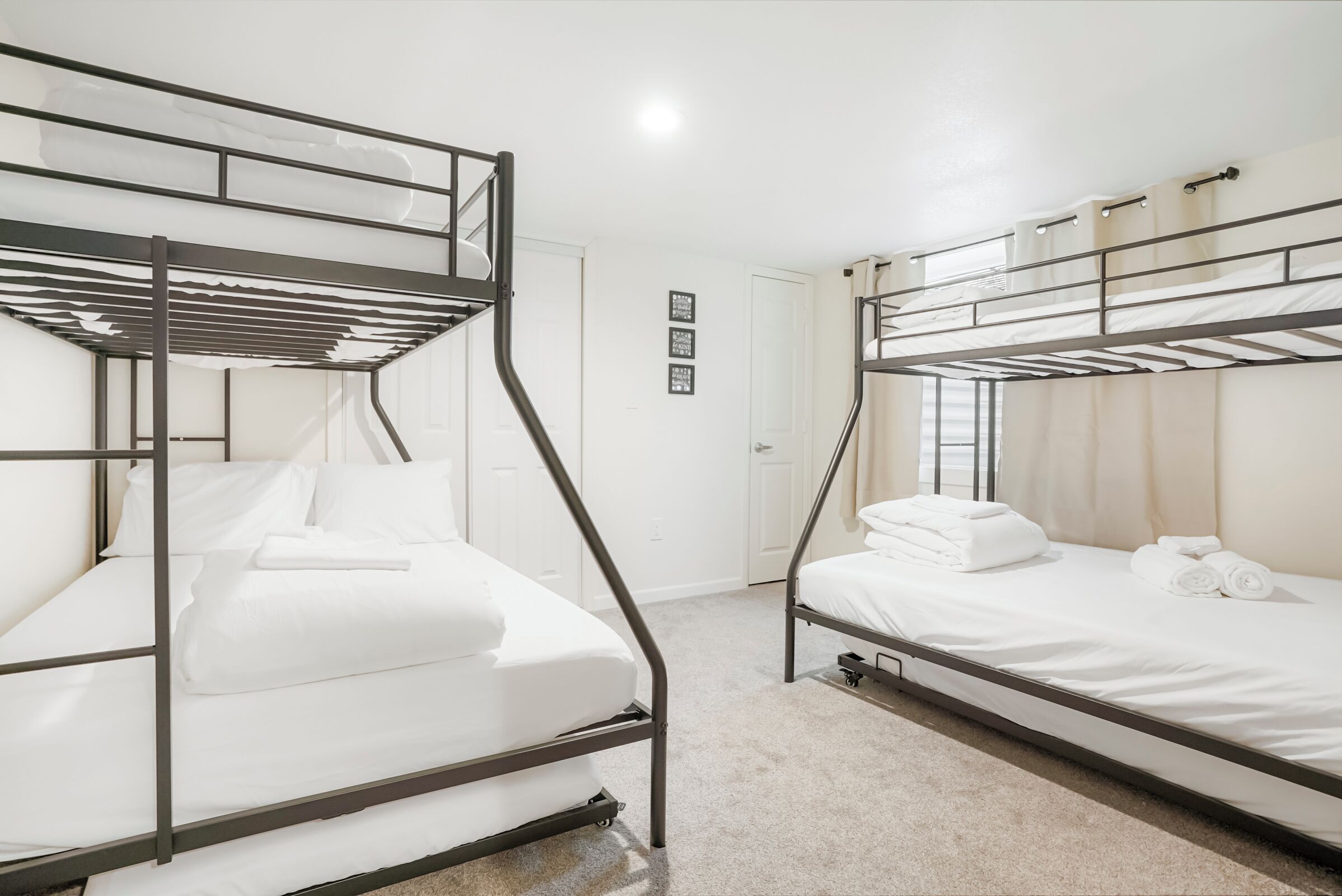 Una habitación con dos literas, ropa de cama blanca y una puerta con un letrero.