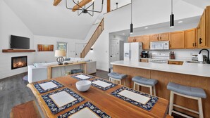 A modern kitchen with wooden cabinets, a central island, and bar stools. - Game Room, FirePit, Screened Porch & Golf Views (Hedgesville)