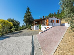Una casa moderna con fachada de piedra, terraza de madera y camino de acceso de grava.