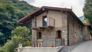 Ein Steinhaus mit Balkon, Betonfundament und Bergblick.