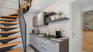 Eine moderne Küche mit einer Holztreppe, Einbauküche, einer Kaffeemaschine und einer Wand mit Steinverkleidung.