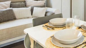 A dining area with a table set for two, including plates, bowls, cutlery, and glasses. - Prestige Family by Interhome (Castiglione della Pescaia)