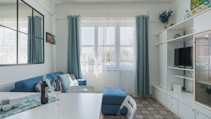 Ein modernes Wohnzimmer mit einem weißen Tisch, einem blauen Sofa und einem Fernseher auf einem Regal.