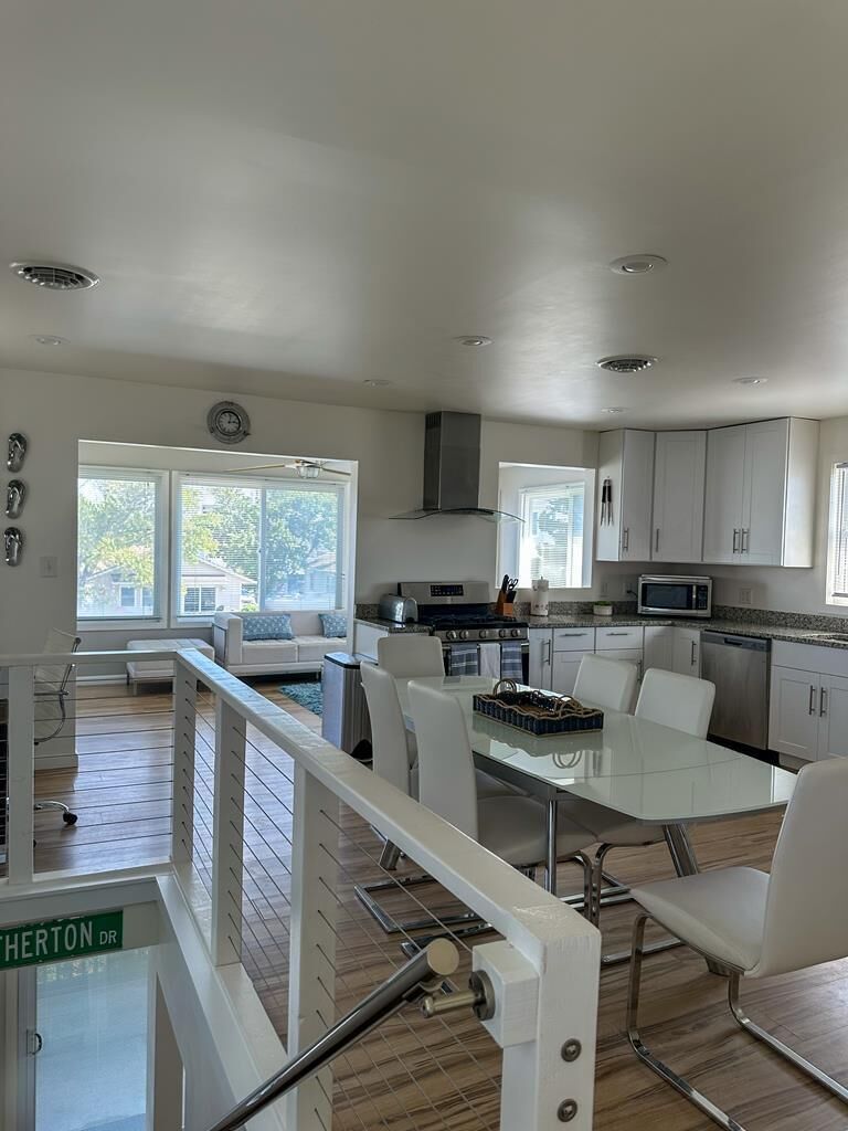 A modern kitchen with white cabinets, a dining table, and chairs.