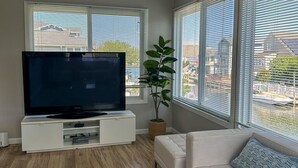 A living room with a flat-screen TV, white sofa, and large windows. - 4BR Home Near the Beach! | Canal Access + Porch (South Bethany)